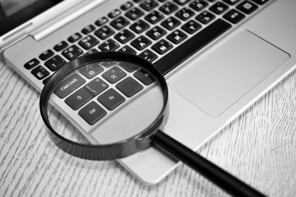 us search online background check service review magnifying glass over laptop keyboard